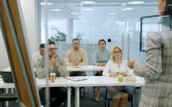 Equipo en sala de reuniones escuchando la presentación de una colega.